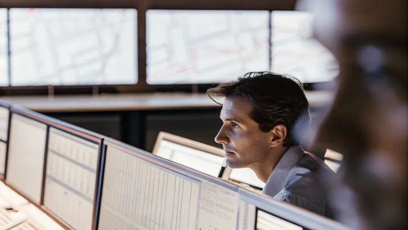 A cybersecurity analyst monitoring multiple screens displaying real-time iGaming platform data and security alerts in a dimly lit operations center
